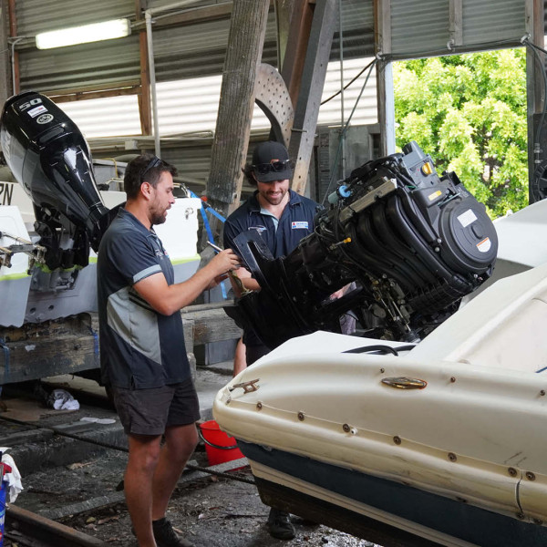 Marine mechanic team servicing an outboard engine Marine mechanic team servicing an outboard engine